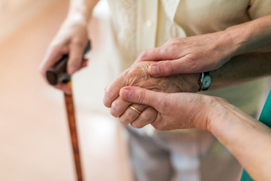 Nurse consoling her elderly patient by holding her hands